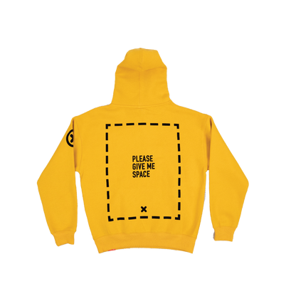A yellow hoodie with a graphic of a dotted-line rectangle covering the majority of the back of the garment. In the center of the rectangle is the text "PLEASE GIVE ME SPACE". Towards the bottom of the inside of the rectangle is an "X". An "X" with a circle around it is on the left-shoulder of the hoodie.