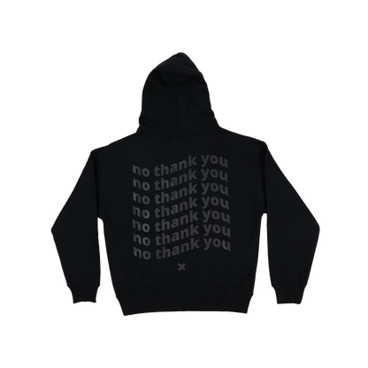 The back of a black long-sleeved hoodie with a graphic of wavy repeated off-black text that says "no thank you" 7 times. The graphic is in the centre of the back of the hoodie. There is an off-black "X" graphic just below the text.